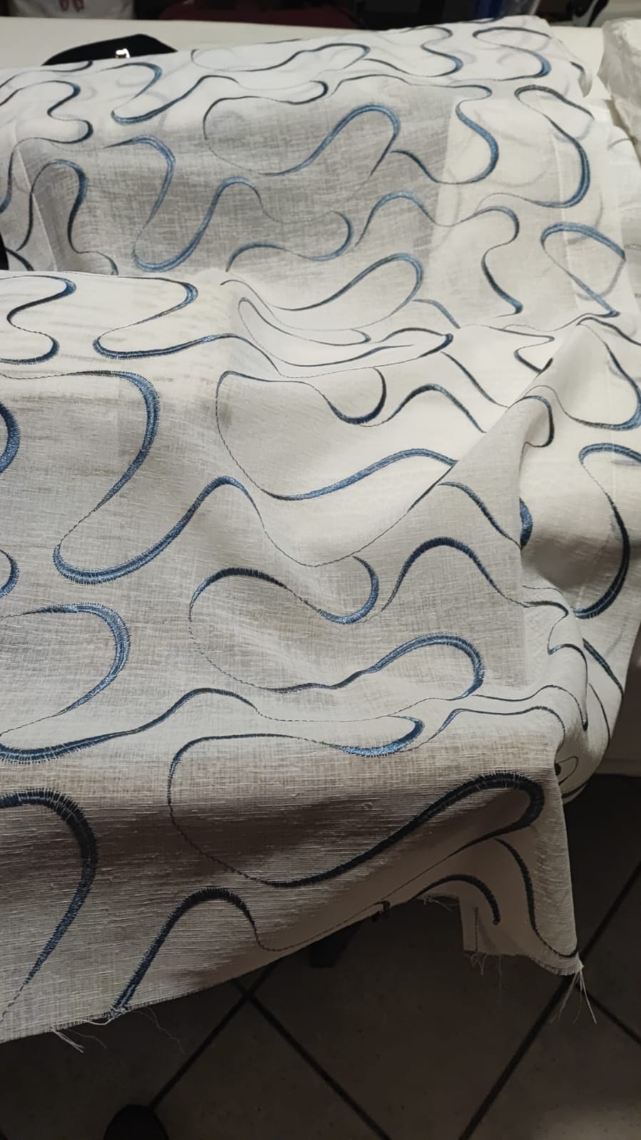 Glass curtain embroidered with waves in white, grey, beige and blue